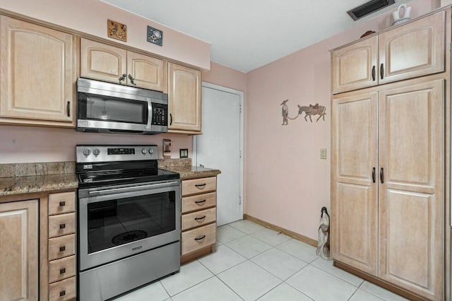 kitchen featuring light stone counters, light brown cabinetry, light tile patterned floors, and appliances with stainless steel finishes