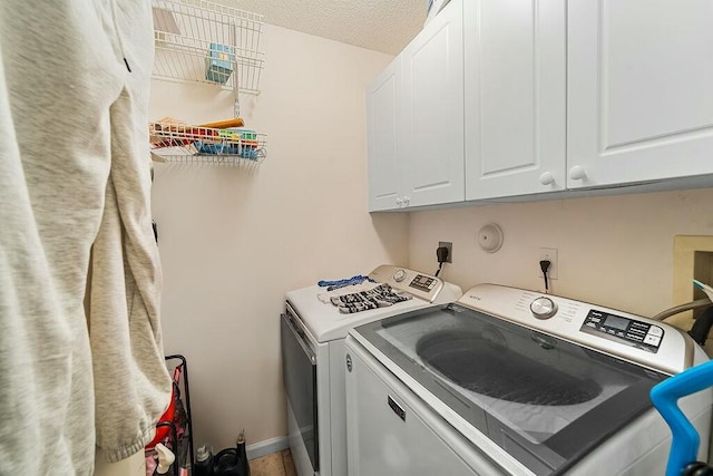 laundry room with washing machine and dryer, cabinets, and a textured ceiling