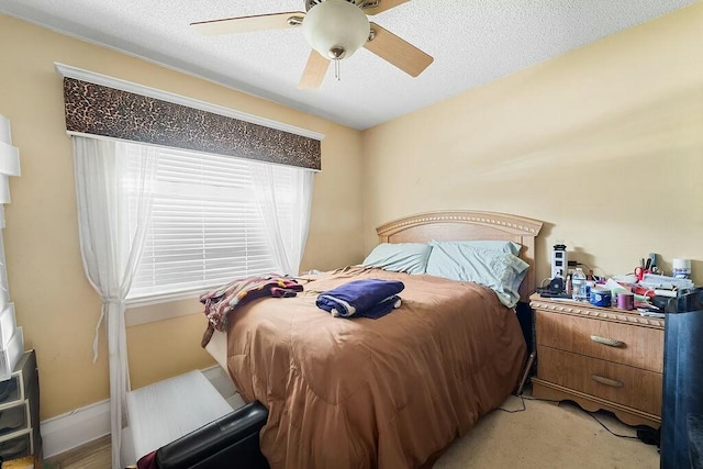 bedroom with ceiling fan, light carpet, and a textured ceiling