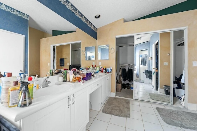 bathroom with vaulted ceiling, tile patterned flooring, vanity, walk in shower, and a textured ceiling