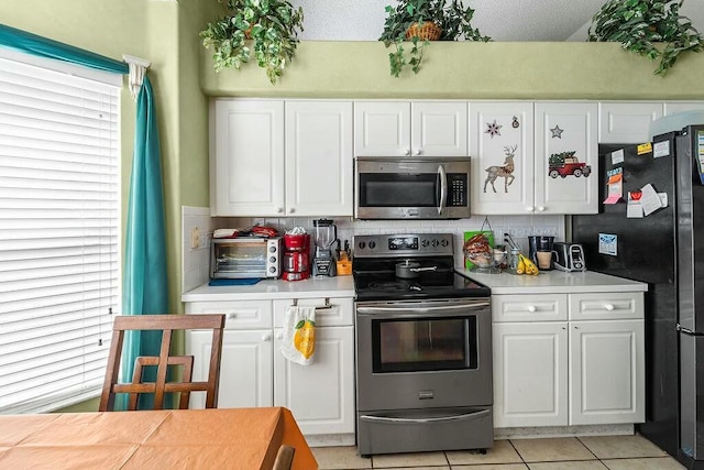 kitchen featuring white cabinetry, appliances with stainless steel finishes, light tile patterned flooring, and decorative backsplash