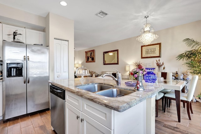 kitchen with stainless steel appliances, sink, a center island with sink, and white cabinets