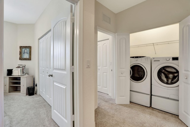 laundry room featuring light carpet and separate washer and dryer