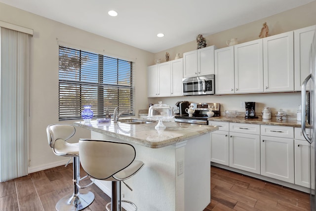 kitchen featuring a kitchen island with sink, sink, stainless steel appliances, and white cabinets