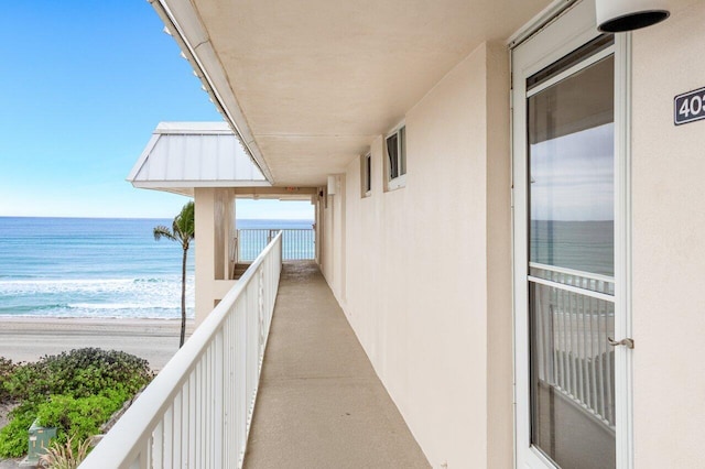 balcony featuring a view of the beach and a water view