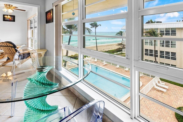 sunroom / solarium featuring a water view and ceiling fan