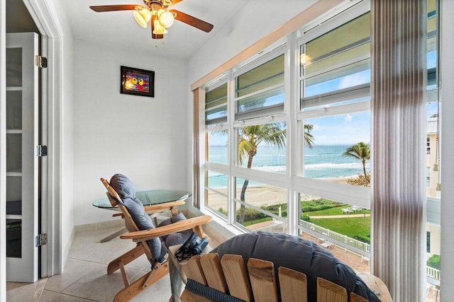 sunroom with ceiling fan and a water view