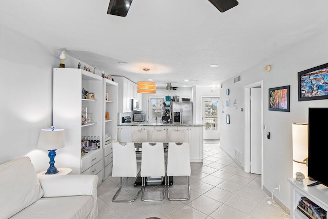 kitchen featuring appliances with stainless steel finishes, white cabinets, a kitchen bar, hanging light fixtures, and ceiling fan