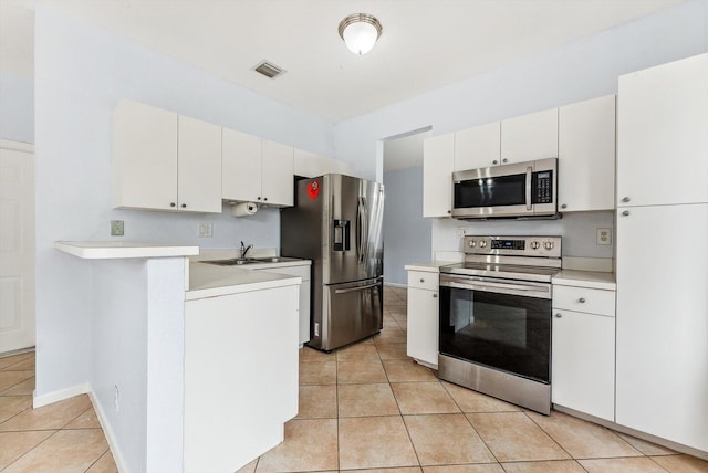 kitchen with appliances with stainless steel finishes, light tile patterned floors, sink, and white cabinetry