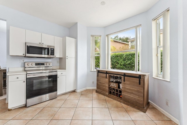 kitchen featuring appliances with stainless steel finishes, white cabinets, and light tile patterned flooring