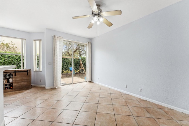 tiled spare room with ceiling fan and plenty of natural light