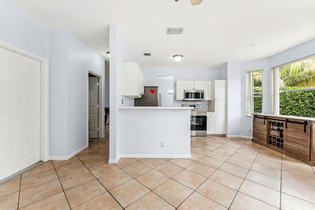 kitchen featuring light tile patterned floors, stainless steel appliances, and white cabinetry