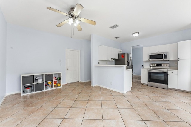 kitchen with appliances with stainless steel finishes, light tile patterned flooring, ceiling fan, kitchen peninsula, and white cabinets