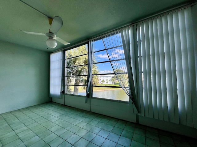 unfurnished sunroom with a water view and ceiling fan