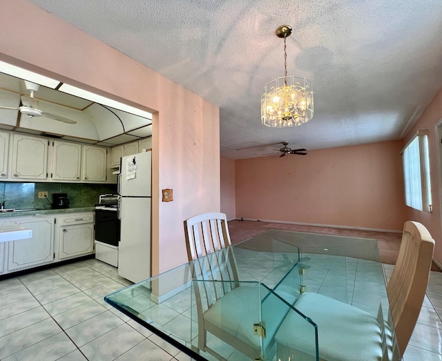 unfurnished dining area featuring light tile patterned floors, ceiling fan with notable chandelier, and a textured ceiling