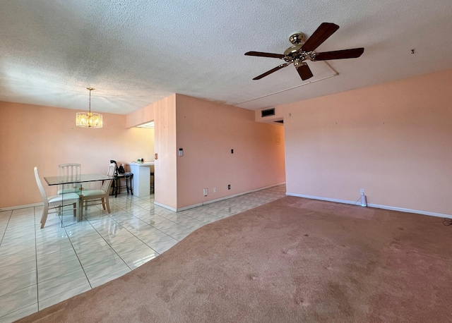 carpeted empty room featuring ceiling fan with notable chandelier and a textured ceiling