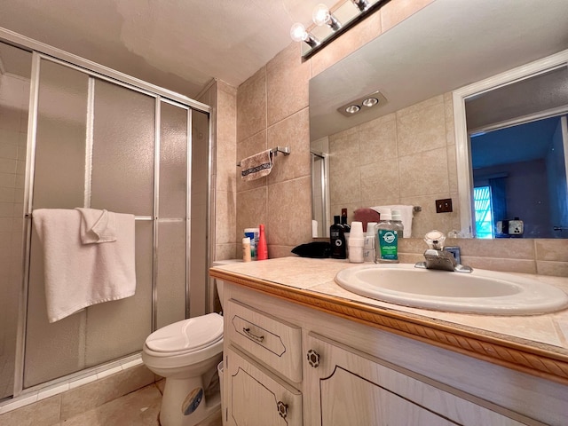 bathroom featuring toilet, tile walls, vanity, a shower with door, and tile patterned flooring