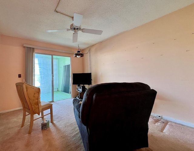 living area featuring ceiling fan, light carpet, and a textured ceiling