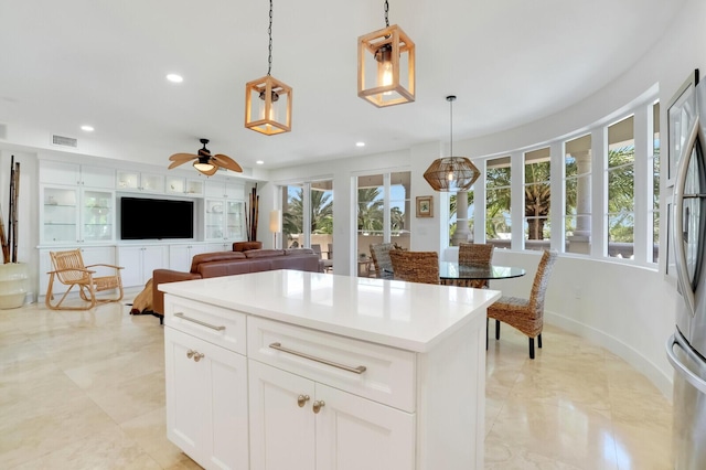 kitchen featuring white cabinetry, a center island, hanging light fixtures, stainless steel fridge, and ceiling fan