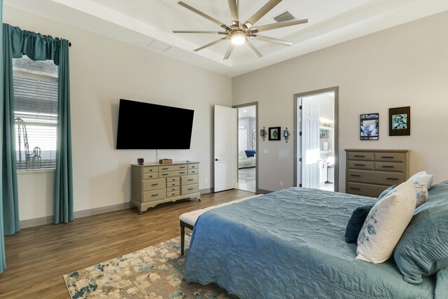 bedroom featuring visible vents, baseboards, ensuite bathroom, wood finished floors, and a ceiling fan