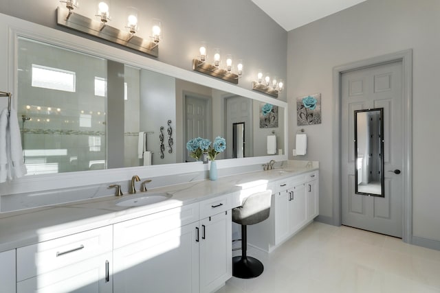 bathroom featuring double vanity, a sink, tile patterned flooring, and a tile shower