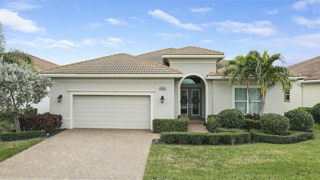 mediterranean / spanish house with a garage and a front lawn