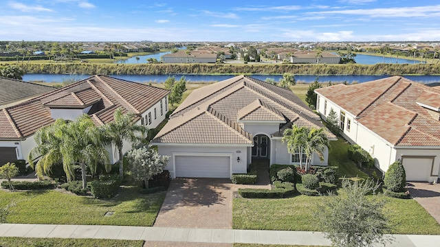 view of front of property featuring stucco siding, a garage, a water view, a tiled roof, and decorative driveway