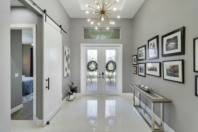 foyer entrance with a notable chandelier, french doors, baseboards, and a barn door