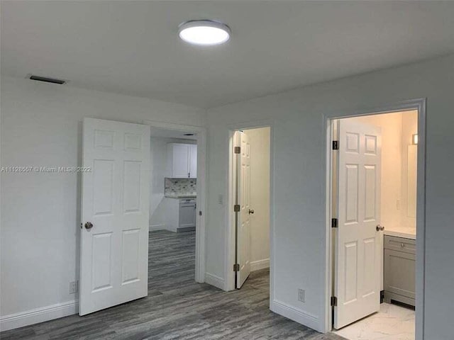 unfurnished bedroom featuring ensuite bath and light wood-type flooring