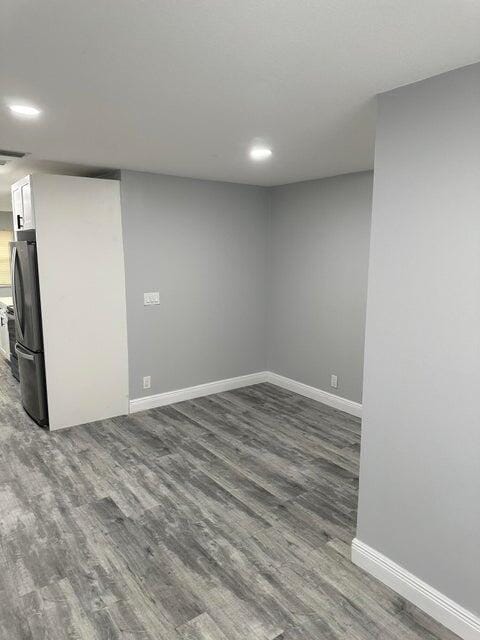 basement featuring wood-type flooring and stainless steel fridge