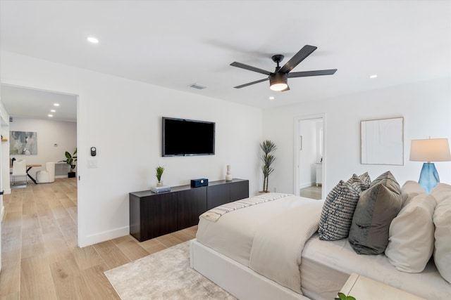 bedroom with ensuite bathroom, light hardwood / wood-style floors, and ceiling fan