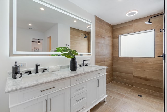 bathroom with a tile shower, vanity, and ceiling fan