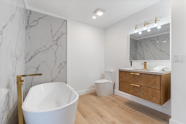 bathroom featuring toilet, wood-type flooring, vanity, and a bathtub