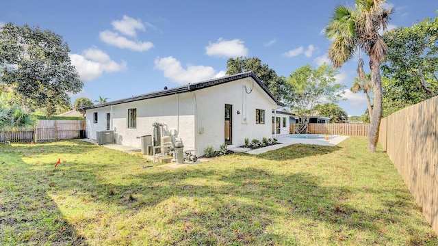 back of house featuring cooling unit, a yard, a fenced in pool, and a patio