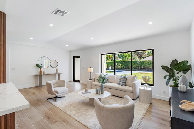 living room featuring lofted ceiling and light hardwood / wood-style flooring