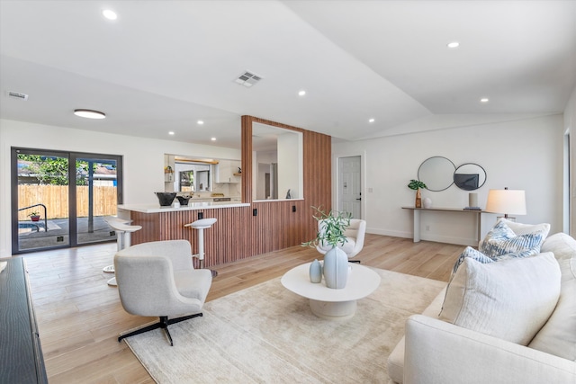 living room featuring light wood-type flooring and vaulted ceiling