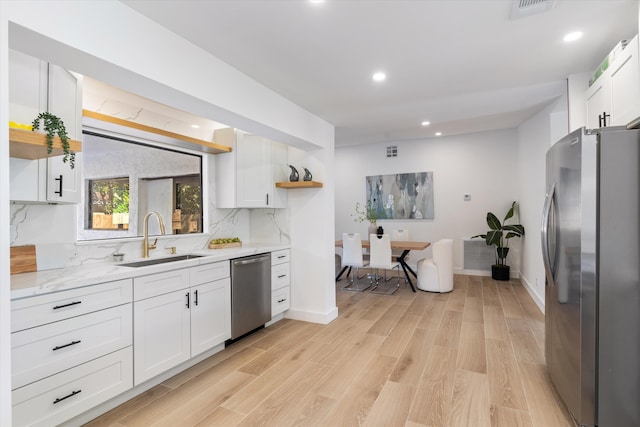 kitchen featuring sink, light hardwood / wood-style flooring, stainless steel appliances, white cabinets, and decorative backsplash