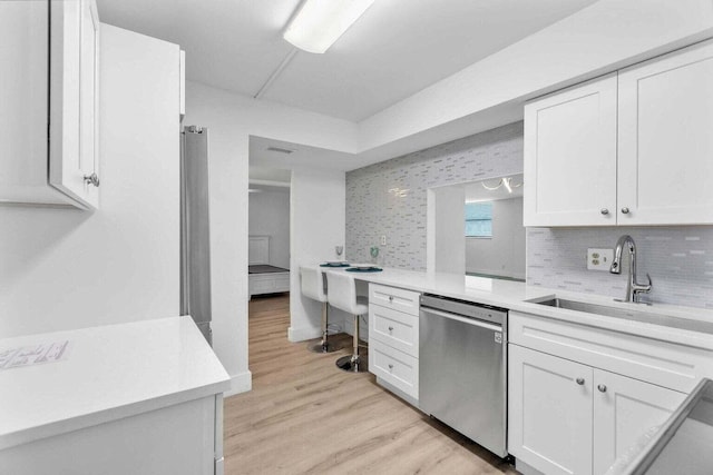 kitchen with sink, light hardwood / wood-style flooring, stainless steel dishwasher, and white cabinets