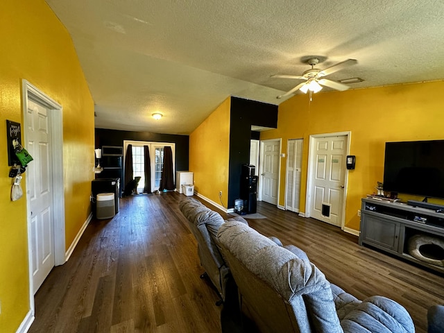 living room featuring ceiling fan, dark hardwood / wood-style flooring, vaulted ceiling, and a textured ceiling