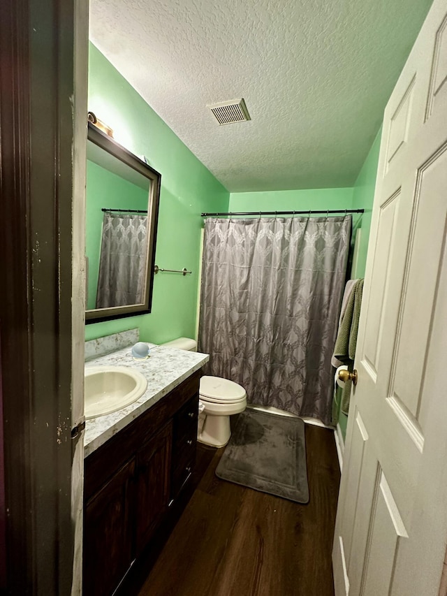 bathroom with toilet, a textured ceiling, vanity, curtained shower, and hardwood / wood-style flooring