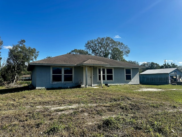 single story home featuring an outdoor structure and a front lawn