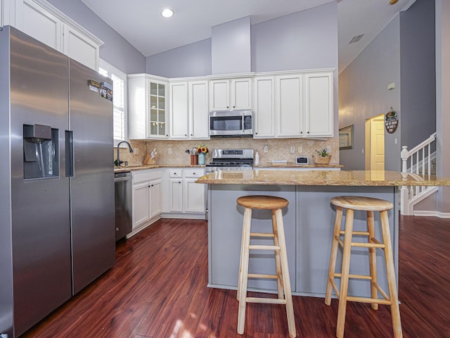 kitchen with white cabinetry, a kitchen breakfast bar, stainless steel appliances, and a center island