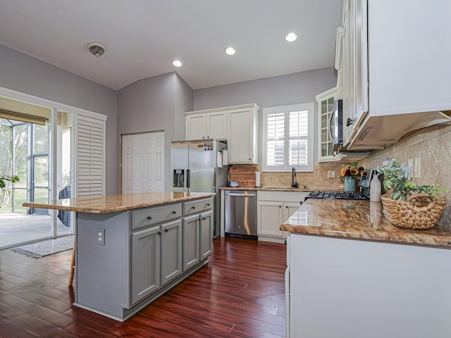 kitchen featuring a kitchen bar, a center island, appliances with stainless steel finishes, gray cabinets, and white cabinets