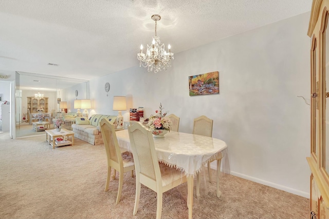 dining room with a chandelier, light carpet, and a textured ceiling