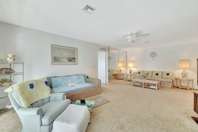 living room with ceiling fan, light colored carpet, and a textured ceiling