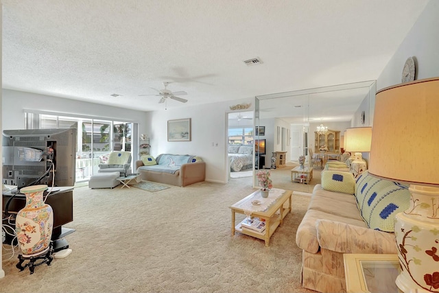 living room with ceiling fan with notable chandelier, a textured ceiling, and carpet