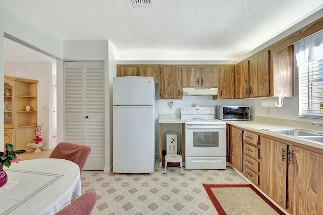 kitchen featuring white appliances, sink, and a textured ceiling