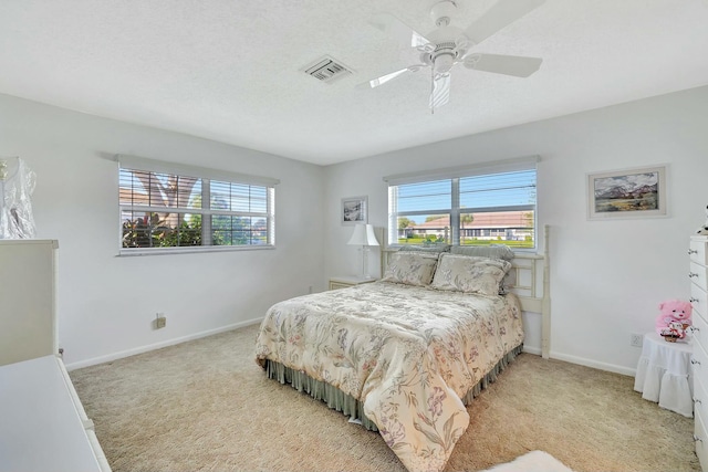 bedroom with ceiling fan, light carpet, and a textured ceiling