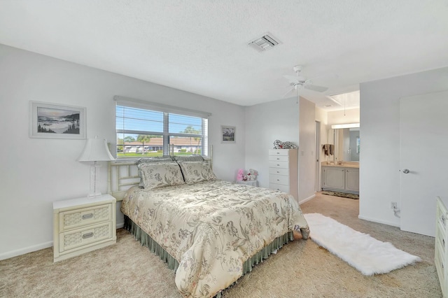 bedroom featuring light carpet, a textured ceiling, ceiling fan, and ensuite bathroom