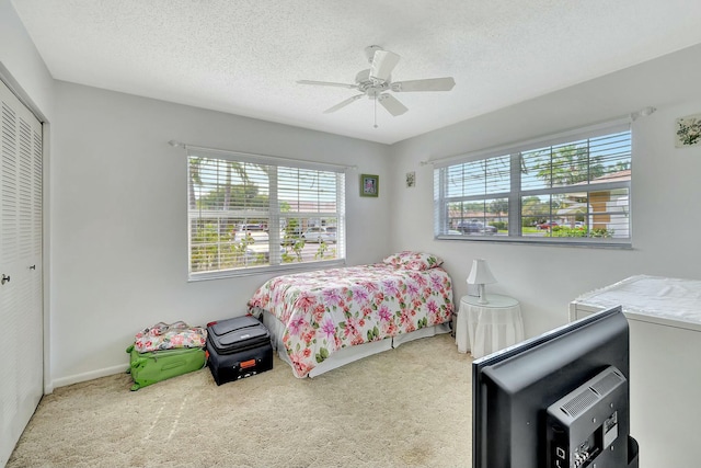 bedroom with ceiling fan, carpet floors, a closet, and a textured ceiling